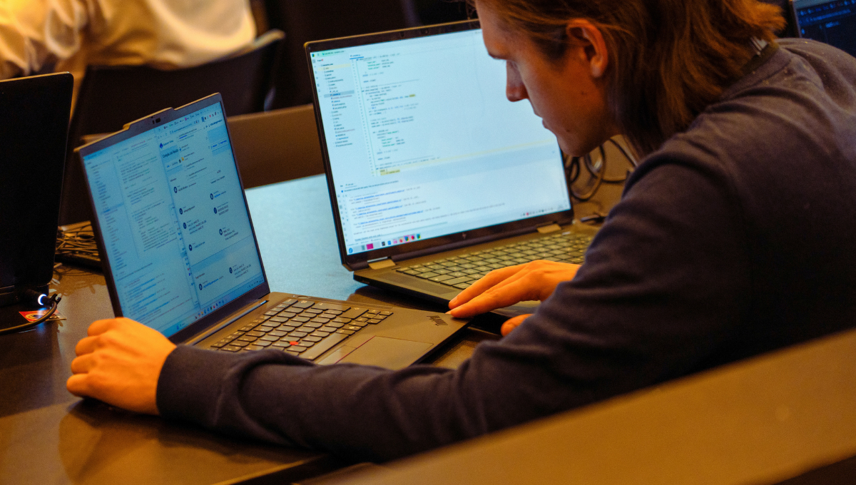 Image of a man programming between two Snapdragon powered laptops. 